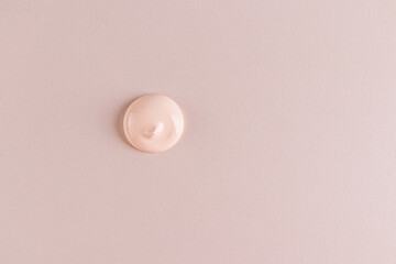 A round sample of liquid foundation powder on a beige background. Delicate texture of foundation in a natural tone. top view. A copy space