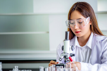 Attractive young Asian scientist woman lab technician assistant analyzing sample in test tube at laboratory. Medical, pharmaceutical and scientific research and development concept	