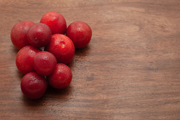 A pile of fresh Cherry Plum (Prunus cerasifera) fruits are arranged on a wooden background.