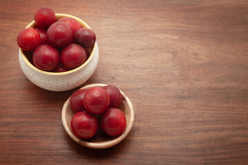 Top view of fresh Cherry Plum (Prunus cerasifera) fruits in a wooden bowl and a ceramic bowl, on a...
