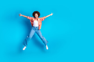 Full size photo of attractive young woman jump star pose dressed stylish checkered clothes isolated on blue color background