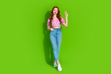 Full length photo of shiny attractive lady dressed print top showing v-sign empty space isolated green color background