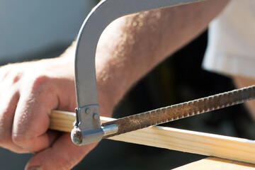 Hand saw with hardened teeth. saw in hand, hacksaw at work. cut the wood plank. close-up. repair concept, construction material cutting, working tool. carpenter at work