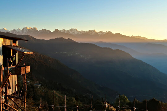 Wooden farmers house in front of the Himalaya Mountain Range in the distance at golden hour, seen on the off-road fride from kathmandu to Salleri, Phaplu, Bupsa, Jubing, Nepal