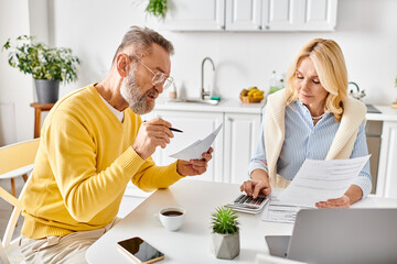 A couple in cozy homewear sit at a table, engrossed in paperwork, discussing and planning for the future.