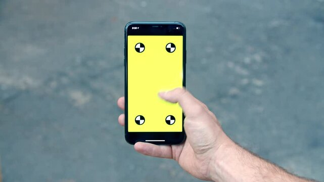 Close-up of iPhone with Green Screen and Tracking Dots, Finger Pressing at Bottom of Screen