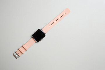 Smart watch with pink rubber bracelet on gray background, flat lay with copy space