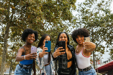 Four female friends enjoying an outdoor selfie session on a sunny day