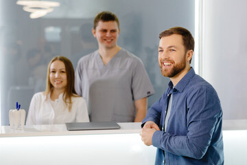 Grateful patient. Man standing at the reception of dental clinic and very pleased for the treatment.