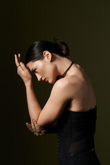 A young woman with brunette hair poses in front of a black background