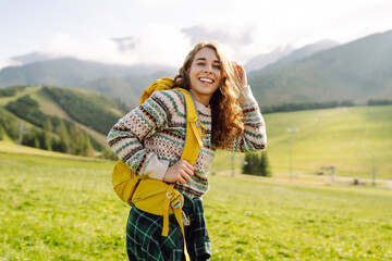 Woman tourist traveler walking on green grass field, top of mountain in  sunny day under sun light. Beautiful mountains landscape.