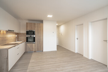 A modern, bright kitchen with white cabinets, wooden countertops, built-in appliances, light wooden...