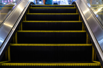 Close up view of an escalator with yellow safety edges, highlighting its steps and modern design.