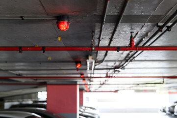 Fire detection system with red lights in a dimly lit parking garage ceiling
