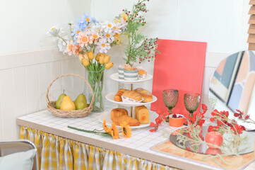 Lovely kitchen counter setup with flowers, fruits, and pastries.