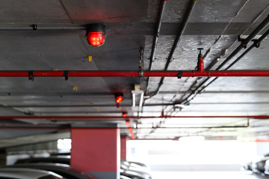Fire detection system with red lights in a dimly lit parking garage ceiling