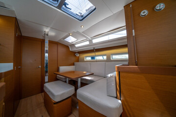 Sailing yacht interior. Double cabin on a charter yacht. Bareboat yacht interior - wood trim, light mattress and bedding, plenty of light from portholes. Comfortable berth for cruise on seas, oceans