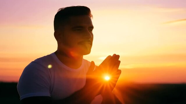 man kneeling in prayer at sunset