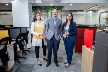 Senior Indian businessman with his colleagues standing in corporate office looking at camera. entrepreneur and workplace concept.