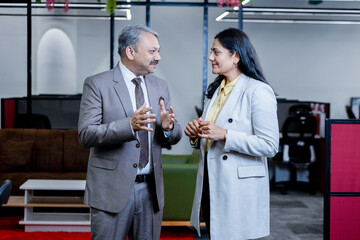 Young indian woman and businessman talking in corporate office for company future planning. workplace and business concept.