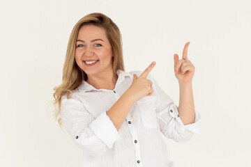 Young confident woman showing logo on empty space. Smiling girl inviting or advertising promo deal, pointing fingers right and looking at camera, white background.