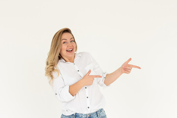 Hey look. Smiling pretty female model pointing fingers right at empty space and inviting to check it out, showing advertisement on white background.