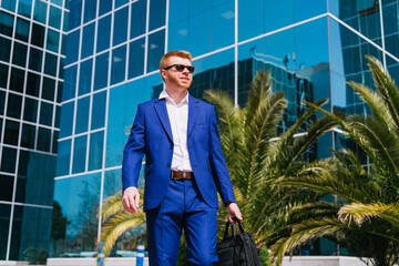 Young businessman walking with briefcase in city business park.