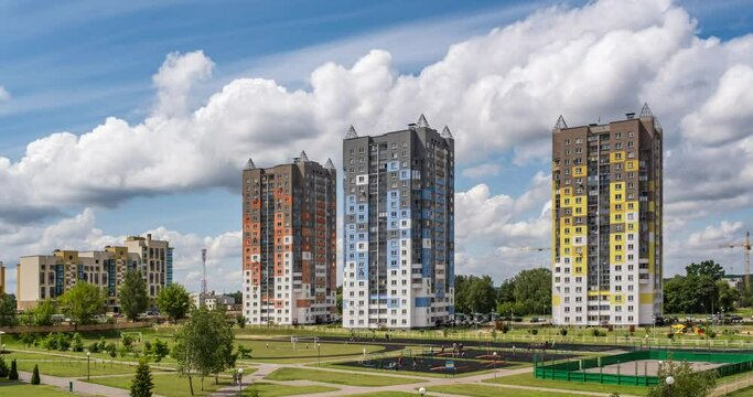 time lapse clip of white fluffy rolling clouds against the background of skyscraper multi-storey apartment buildings