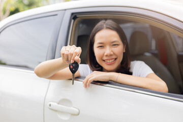 close up adult asian woman hand outstretch from window's car and hold key for rental business and insurance concept