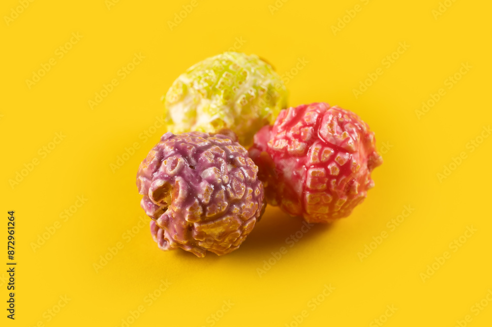 Wall mural Colored fruity popcorn on yellow background