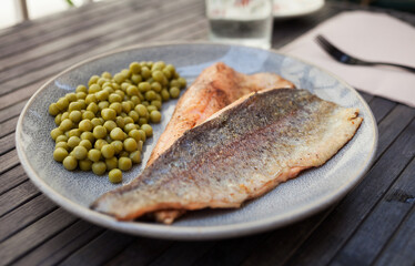 Fried trout fillets served with green peas