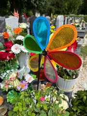 Colorful wind wheel on the tombstone in the public cemetery