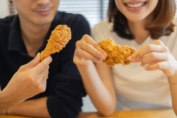 close up couple asian woman and man smile with showing fried chicken meal for eat in living room at home for relaxing lifestyle and fast food concept