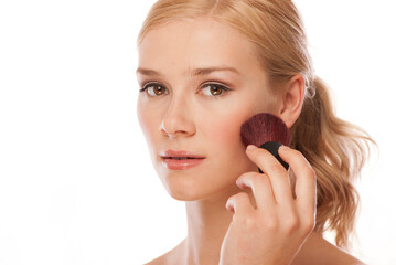 pretty woman applying make up with a powder brush