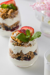 Yogurt with crispy granola, berries and mint leaves for a delicious breakfast. Healthy eating.