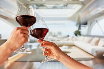 Romantic date on luxurious yacht. People, man and woman clinking glasses with red wine, celebrating and relaxing while sailing on sea. Concept of summer, vacation, travelling, relaxation, nature