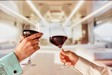 Cheers, celebratory toast. People holding glasses with red wine, clinking against luxurious background of yacht. Concept of summer, vacation, travelling, relaxation, nature