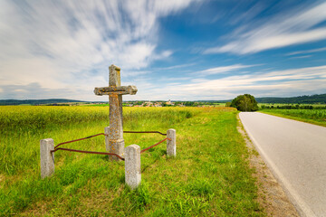 a stone cross by the road in South Bohemia near the village of Sepekov. Panoramic view of the village of Sepekov. Photographed on long exposure.