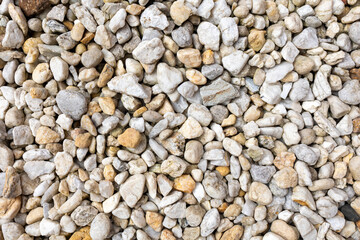 An assortment of diverse, small to medium-sized rocks and pebbles in a range of colors including grays, whites, and beiges, creating a natural and textured surface pattern.