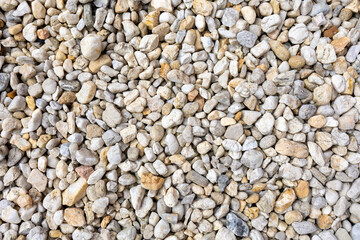 An assortment of diverse, small to medium-sized rocks and pebbles in a range of colors including grays, whites, and beiges, creating a natural and textured surface pattern.