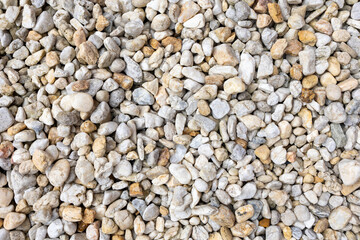 An assortment of diverse, small to medium-sized rocks and pebbles in a range of colors including grays, whites, and beiges, creating a natural and textured surface pattern.