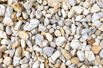 An assortment of diverse, small to medium-sized rocks and pebbles in a range of colors including grays, whites, and beiges, creating a natural and textured surface pattern.