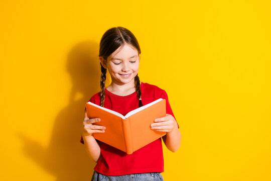 Portrait of cute little girl read book empty space wear t-shirt isolated on yellow color background