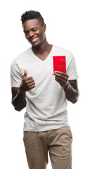 Young african american man holding passport of Switzerland happy with big smile doing ok sign, thumb up with fingers, excellent sign