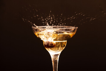 glass with splashes of champagne from cherry berries on a dark background.