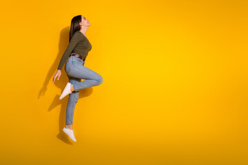 Full body photo of attractive teen woman profile jump graceful dressed stylish khaki clothes isolated on yellow color background