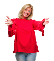 Middle age blonde woman over isolated background looking at the camera smiling with open arms for hug. Cheerful expression embracing happiness.