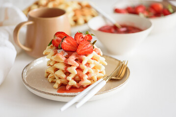 Belgian waffles with strawberries and fresh jam on white table. Summer food concept. Soft focus