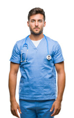 Fototapeta premium Young handsome doctor man over isolated background with serious expression on face. Simple and natural looking at the camera.