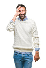 Fototapeta premium Adult hispanic man wearing winter sweater over isolated background doing ok gesture with hand smiling, eye looking through fingers with happy face.